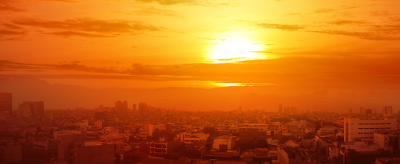 Sunrise over a cityscape with buildings silhouetted against a vibrant orange sky.