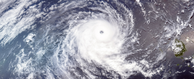 Satellite view of a large hurricane over the ocean with distinct eye and spiraling cloud bands.