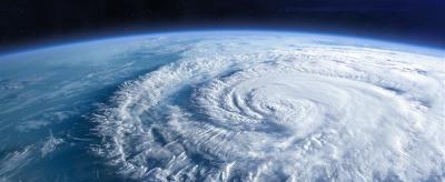 Satellite view of a swirling cyclone over the ocean with curved white clouds and deep blue water beneath.