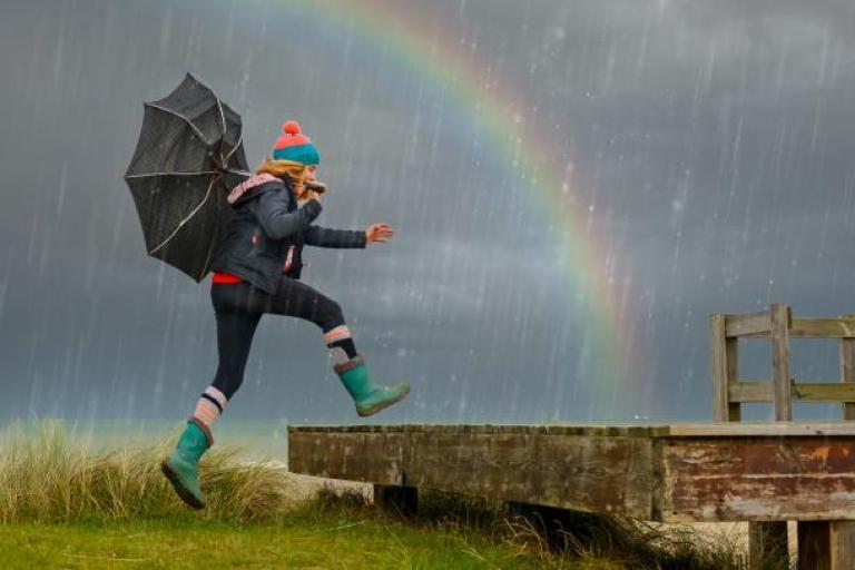 Woman walking in front of a rainbow