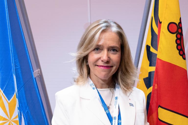 Celeste Saulo in front of the WMO and Geneva Canton flags