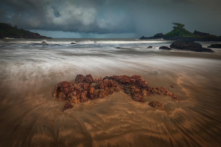 A beach with rocks and a stormy sky.