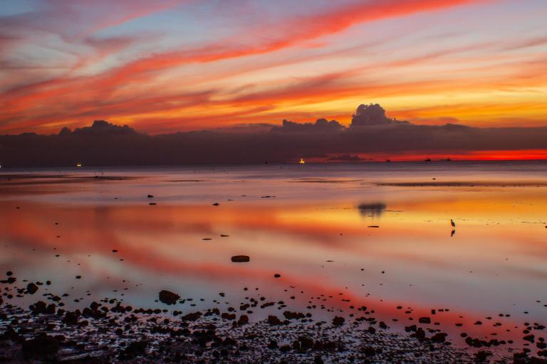 A colorful sunset is reflected in a body of water.