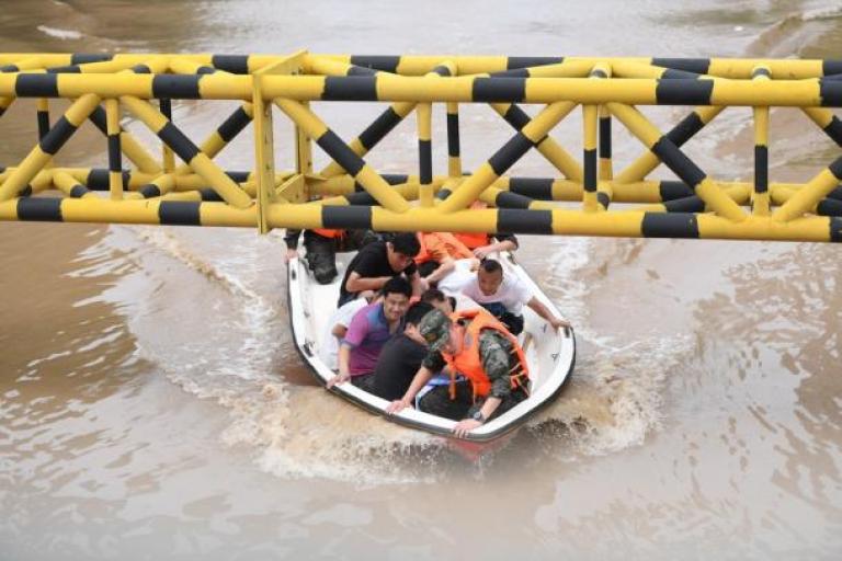 A group of people riding a boat in a flooded area.