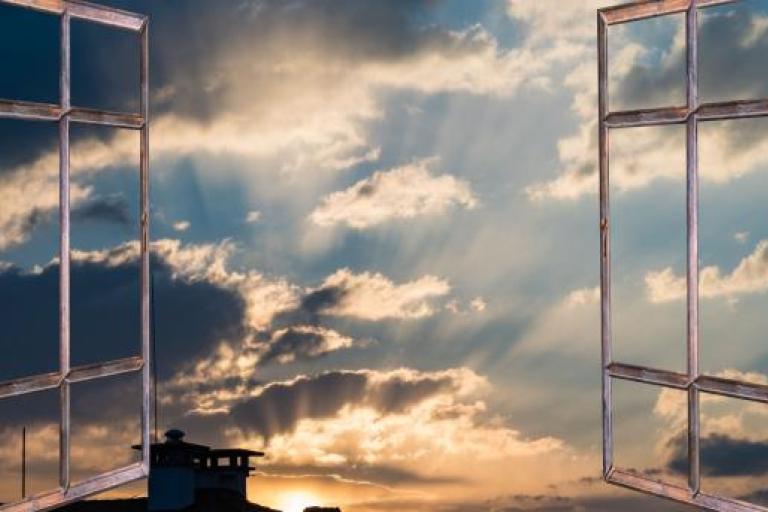 An open window with a view of the sky and clouds.
