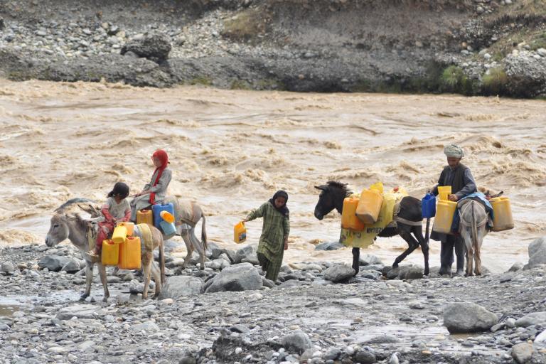 A group of people on donkeys carrying water jugs.