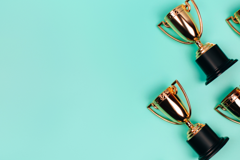 A group of gold trophies on a turquoise background.
