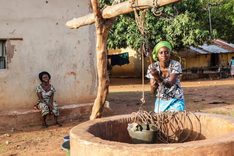 A woman is washing clothes in a well in a village.