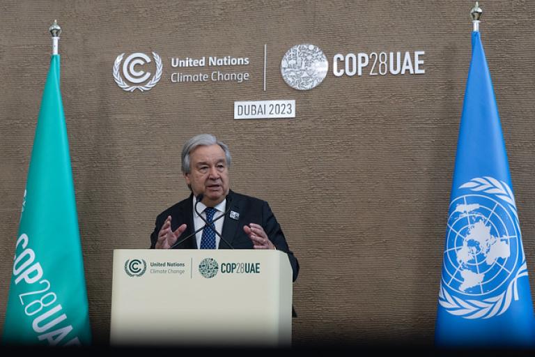 A man standing at a podium in front of flags.