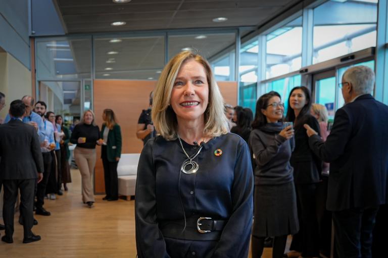 A woman in a room with people in the background.