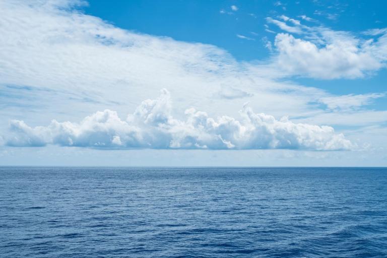 Expansive ocean under a wide sky with fluffy clouds.