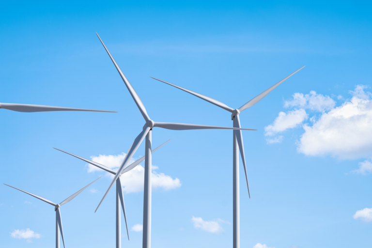 A row of wind turbines against a clear blue sky with scattered clouds.