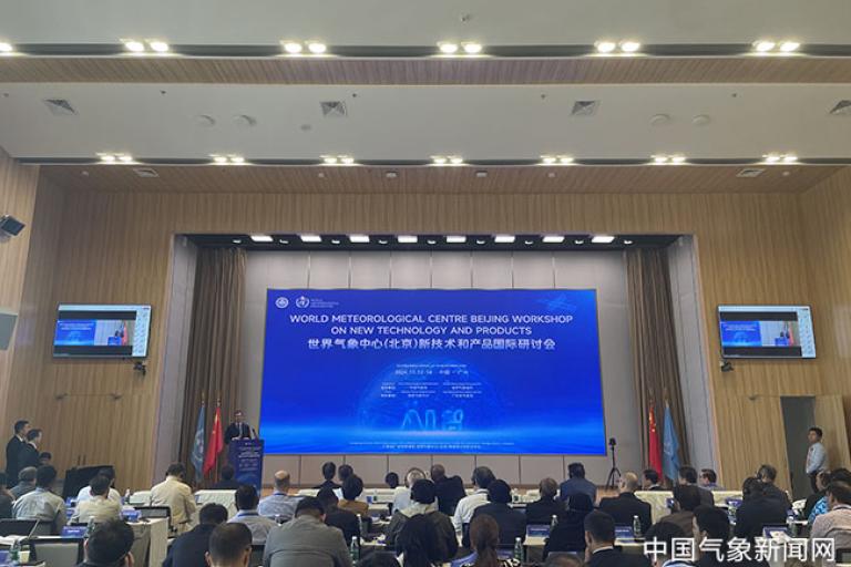 Conference room with people attending the World Meteorological Centre Beijing Workshop on new technology and products. Large screen displays workshop details.