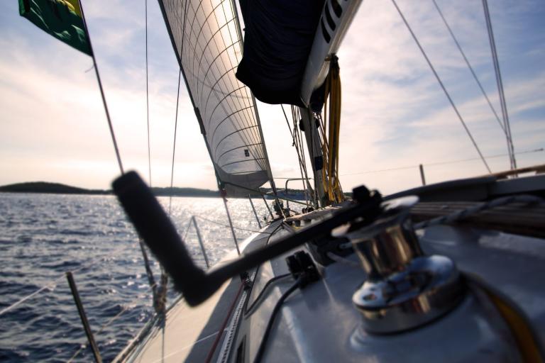 View from a sailboat on the water, showing sails and rigging against a clear sky.