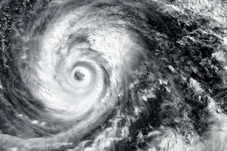 Satellite image of a swirling hurricane with a distinct eye at the center, surrounded by dense cloud formations.