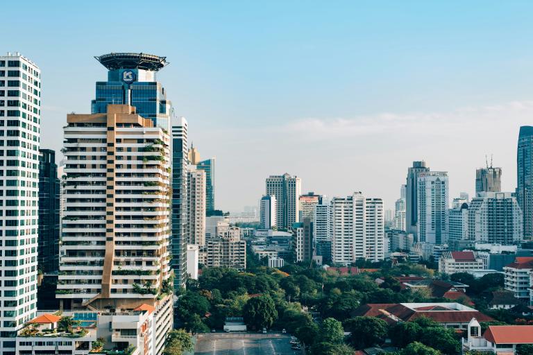City skyline featuring modern high-rise buildings and green spaces under a clear blue sky.