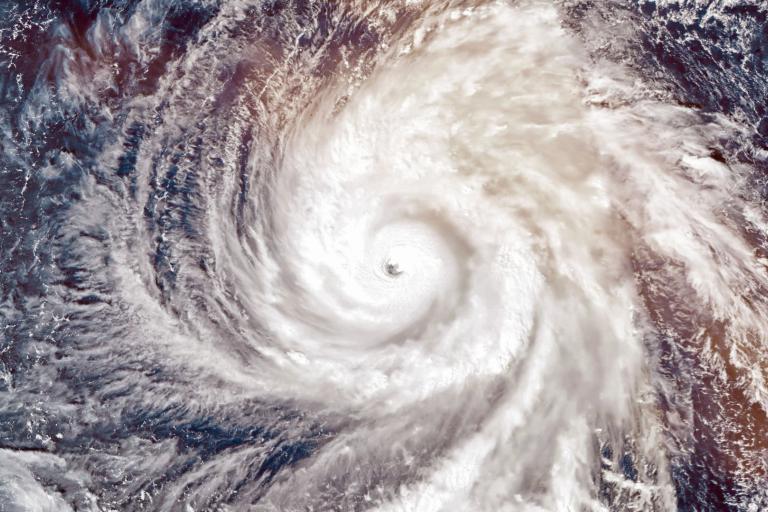 Satellite view of a swirling hurricane over the ocean, showing a distinct eye at the center surrounded by clouds.