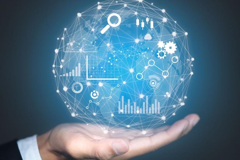 A hand holds a digital globe with interconnected icons and graphs representing data analytics, technology, and global connectivity on a blue background.