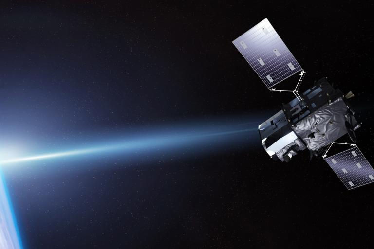A satellite with solar panels orbits Earth in space, with the planet’s blue surface and a bright light visible on the left side.