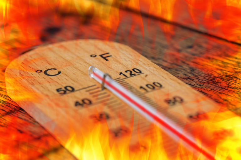 A thermometer shows high temperatures in both Celsius and Fahrenheit, surrounded by flames, suggesting intense heat or extreme temperature.