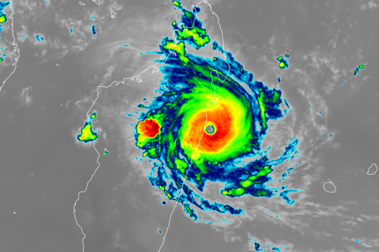 Infrared satellite image showing a strong cyclone with a defined eye making landfall on a coastal region, with intense rain bands surrounding the center.