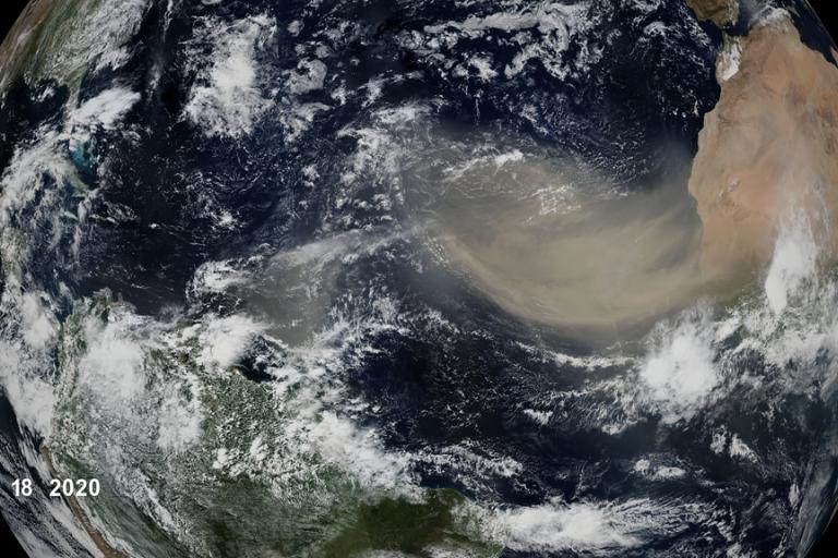 Satellite view of Earth showing a large Saharan dust plume moving westward from Africa over the Atlantic Ocean toward the Americas, dated June 18, 2020.