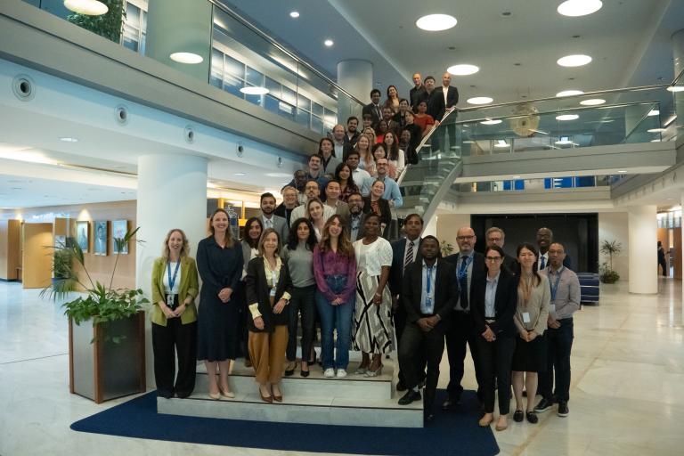 A large group of people posing for a photo on the stairs of a modern office building lobby.