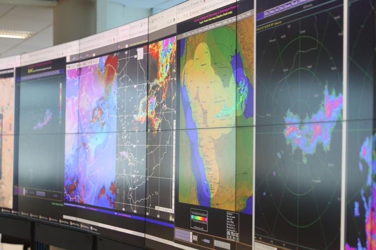 A wall of monitors displaying meteorological radar maps and weather data.