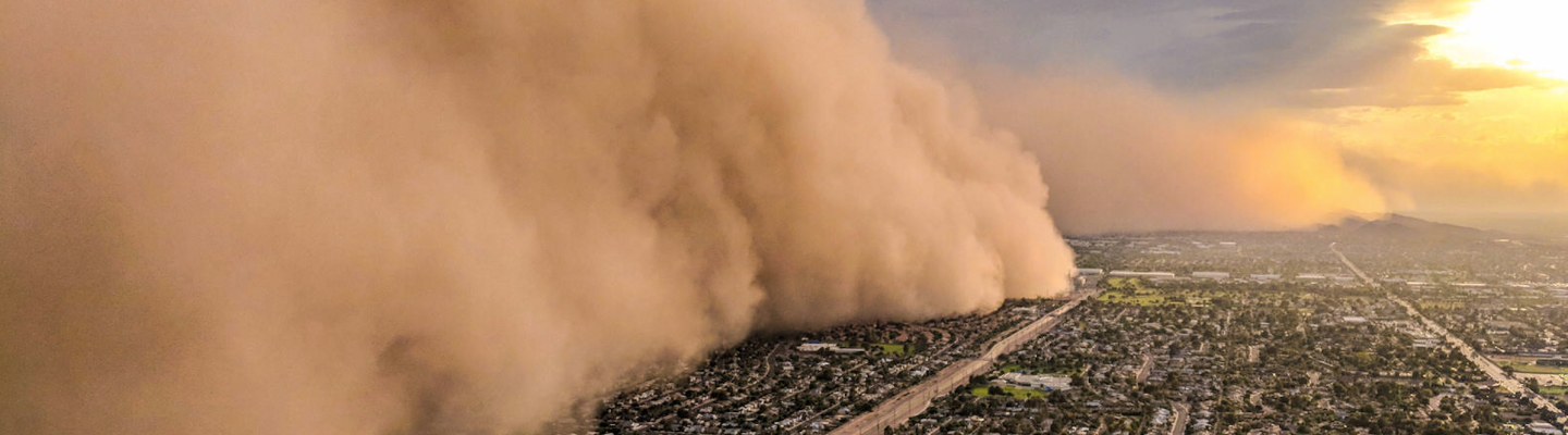 A huge cloud of sand blows over a city.