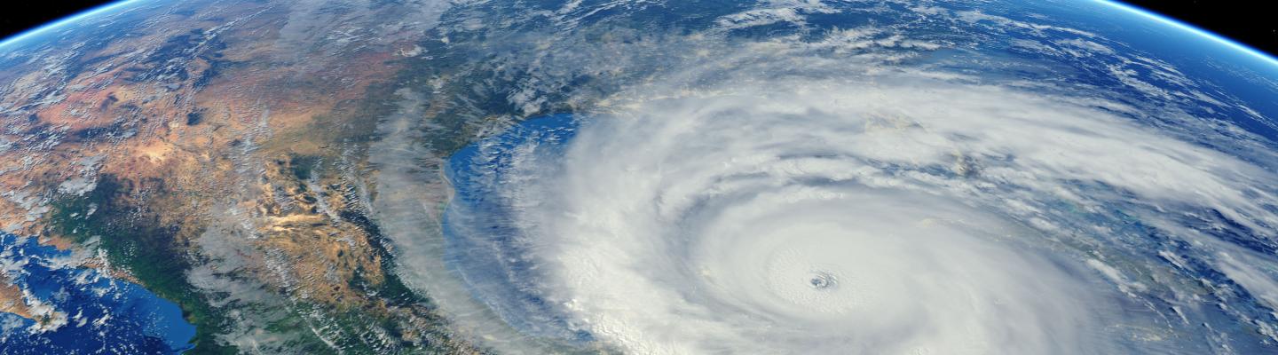 Satellite view of a large, swirling hurricane over the ocean near a continent, with a clear eye at the center and surrounding cloud bands.