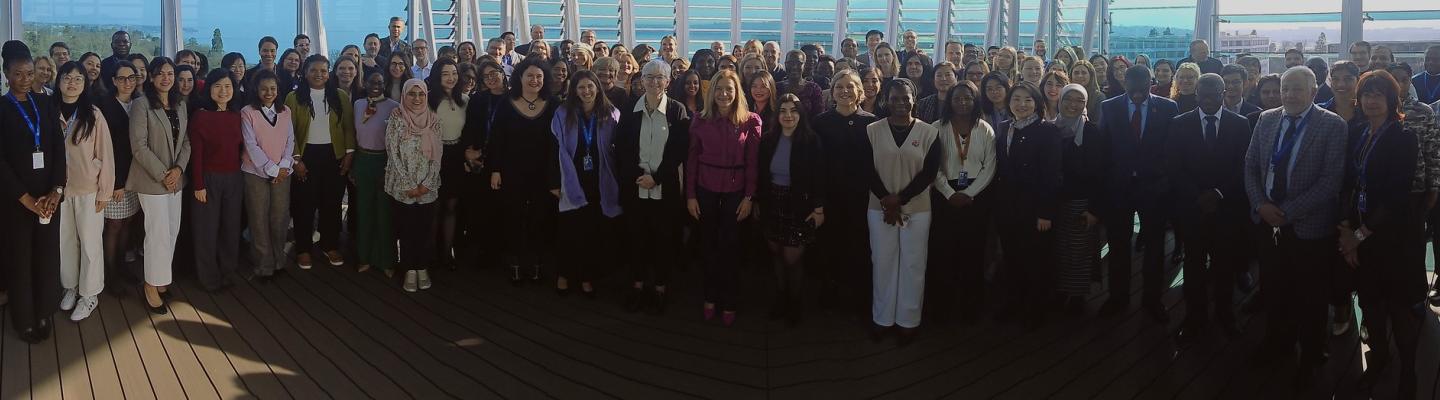 A large group of people posing for a photo on a deck overlooking a body of water.