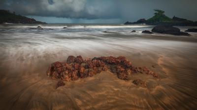 Stormy skies loom over a rocky shoreline with dynamic ocean waves.