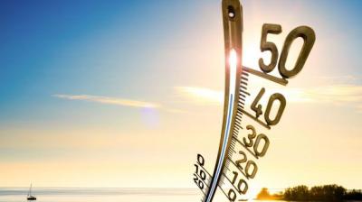 a thermometer on a beach with a boat in the background.