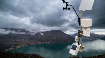 A weather station on top of a mountain overlooking a lake.