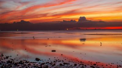 A colorful sunset is reflected in a body of water.