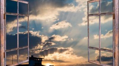 An open window with a view of the sky and clouds.
