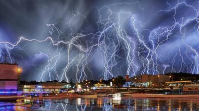 Lightning strikes over a city at night.