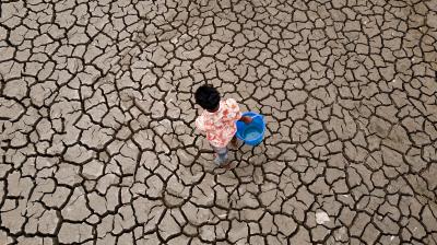An aerial view of a child walking across a dry field.