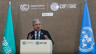 A man standing at a podium in front of flags.