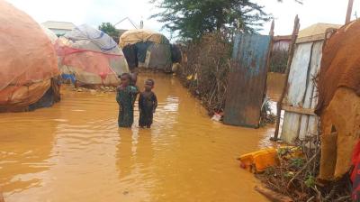 A boy standing in a flooded area near tents.