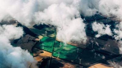An aerial view of wind turbines and green fields.