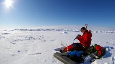 A man sitting in the snow with a backpack.