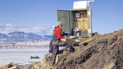 A man standing on top of a mountain with a laptop computer.