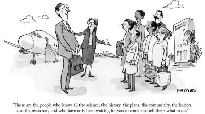 A person in a suit gestures to a smiling group of diverse people while talking to another suited individual at an airport. An airplane is partially visible in the background. Caption reads: "These are the people who know all the science, the history, the plans, the community, the leaders, and the resources, and who have only been waiting for you to come and tell them what to do.