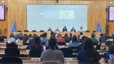A climate action panel discussion takes place with five speakers on stage and an audience seated in front. The event is part of "The People's Climate Vote" by various environmental organizations.