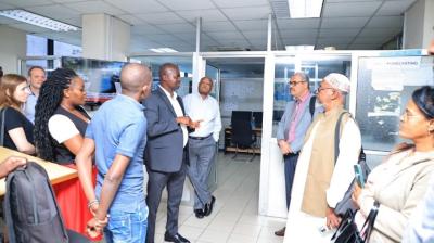 Group of people in an weather forecasting centre, with one individual in a suit speaking while others listen attentively.