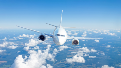 A passenger airplane flying above the clouds against a blue sky.