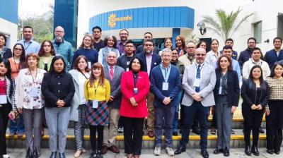 A group of people standing on steps outside a building with "Senamhi" written on it, smiling at the camera.
