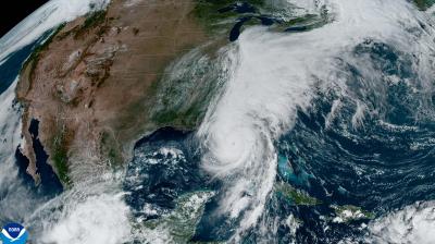 Satellite image of a large storm system over the southeastern United States and Gulf of Mexico, with dense cloud cover and a visible storm eye near the center.