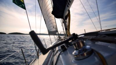 View from a sailboat on the water, showing sails and rigging against a clear sky.